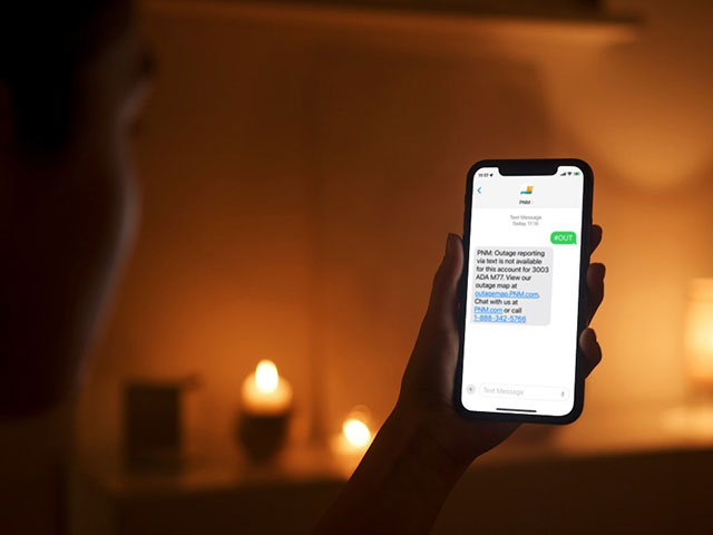 Woman in a candlelit room looking at her phone